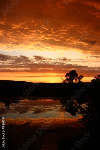 Colorful fiery sunset with a cloudy sky over the river, clouds painted in rich colors © PhotoChur