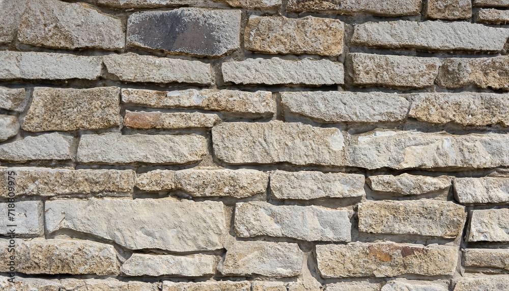 Fototapeta premium wall of stones as a texture for background; gray beige stone bricks close-up