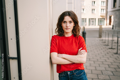 Konstfotografi Confident 25-Year-Old Woman Poses with Crossed Arms, Gazing Sternly in Urban Set