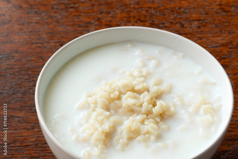 rice porrige. there is a white deep plate with milk rice porridge on a wooden table, breakfast concept rice porrige. there is a white deep plate with milk rice porridge on a wooden table, breakfast concept