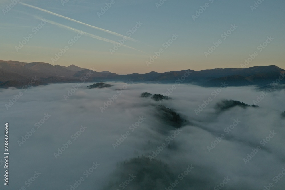 Aerial view of beautiful mountains covered with fluffy clouds in morning
