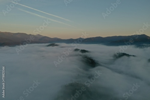 Aerial view of beautiful mountains covered with fluffy clouds in morning © New Africa