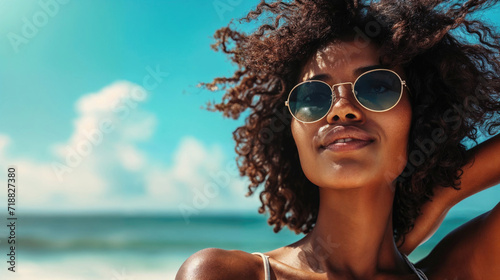 Confident black woman in sunglasses on the beach.