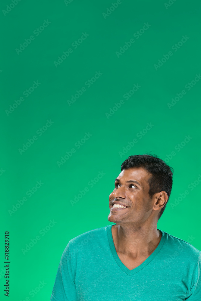 Excited Indian man looking up. Against green background. Excited Indian man looking up. Against green background.