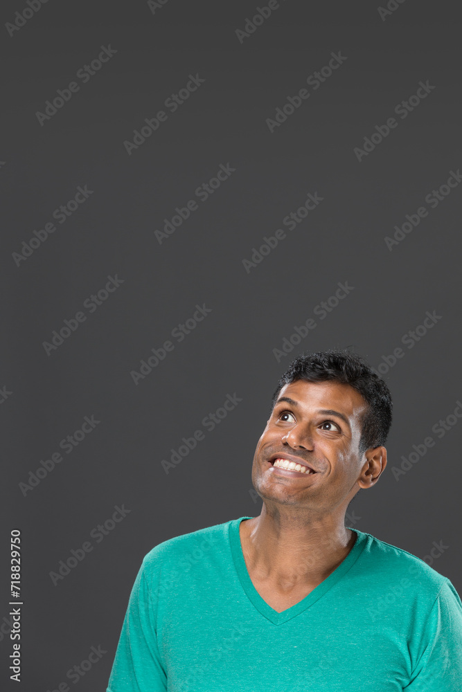 Excited Indian man looking up. Against grey background. Excited Indian man looking up. Against grey background.