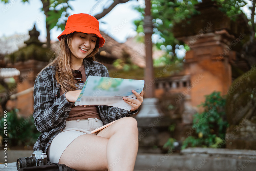 attractive Asian female tourist looking at a map of a tourist destination during a sit down rest with copyspace