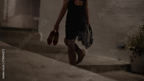 Woman walks home barefoot at night after a party. photo