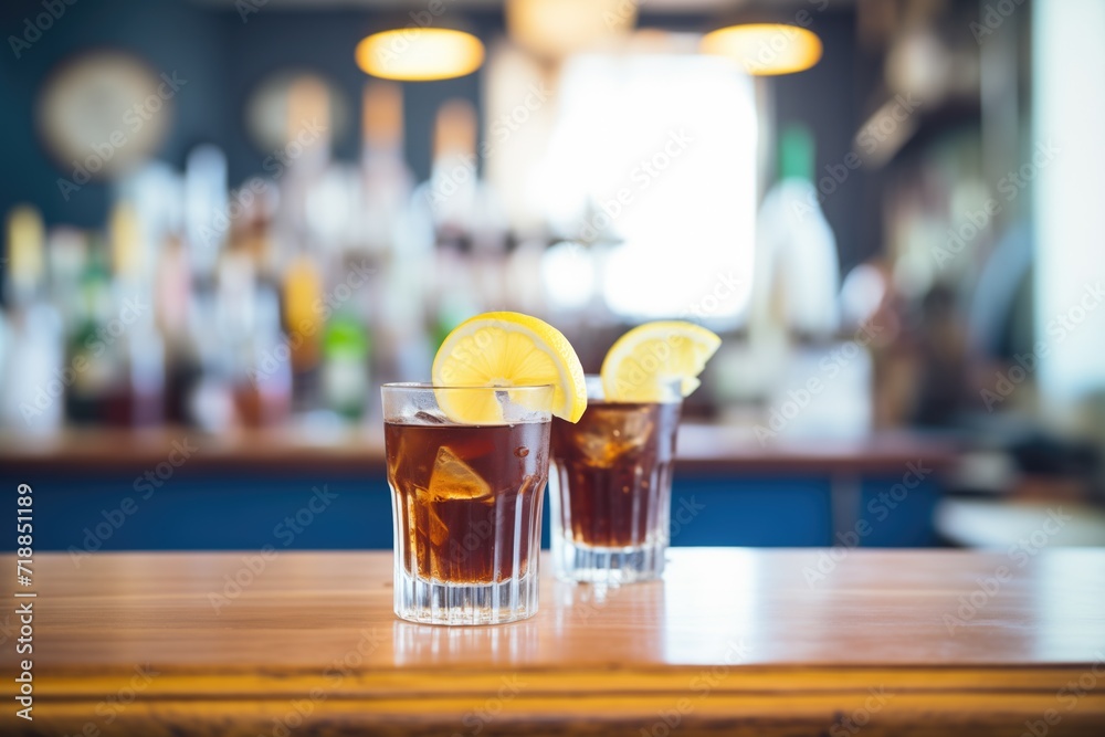two glasses of cola with lemon wedges on a bar two glasses of cola with lemon wedges on a bar