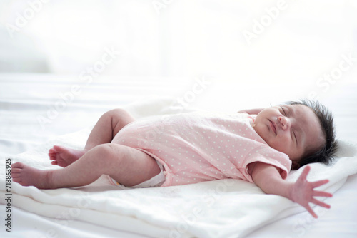 A cute little baby  not yet a month old  lying on bed in bedroom