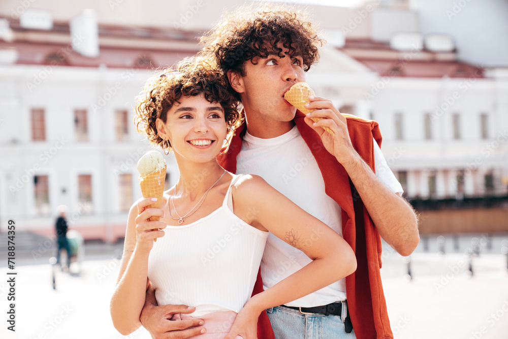 Smiling beautiful woman and her handsome boyfriend. Woman in casual summer clothes. Happy cheerful family. Couple posing on the street background at sunny day. Eating tasty ice cream in waffles cone