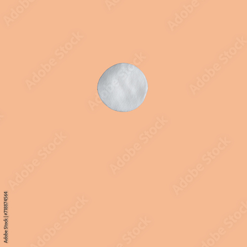 detail of a cotton disk for facial cleansing on peach fuzz background