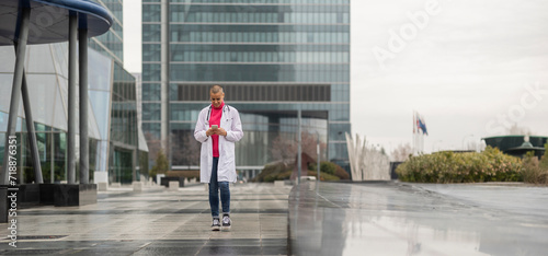 young adult woman manager doctor walking outside the hospital typing on her mobile phone © PintoArt