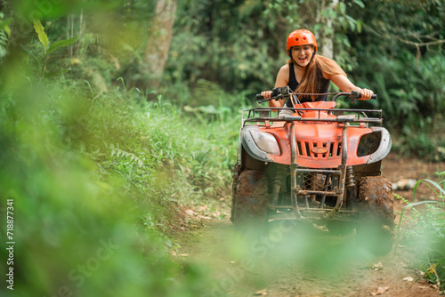 beautiful asian woman riding the atv happily through the atv arena spending her holiday photo