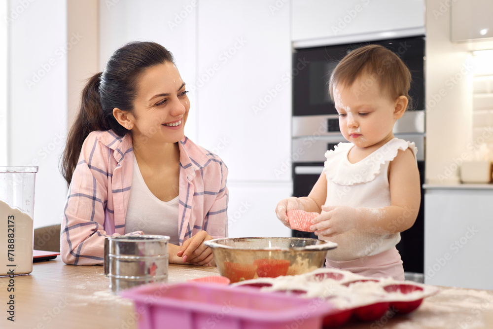 mother and little baby girl preparing the dough in the kitchen, child cooking cookies. mother and little baby girl preparing the dough in the kitchen, child cooking cookies.