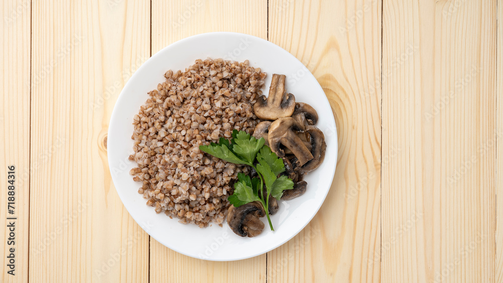 Buckwheat porridge with boiled mushrooms, willow herbs on wooden background Buckwheat porridge with boiled mushrooms, willow herbs on wooden background