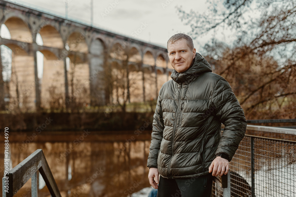 Timeless Elegance: 40-Year-Old Man in Stylish Jacket by Neckar River and Historic Bridge in Bietigheim-Bissingen, Germany Timeless Elegance: 40-Year-Old Man in Stylish Jacket by Neckar River and Historic Bridge in Bietigheim-Bissingen, Germany