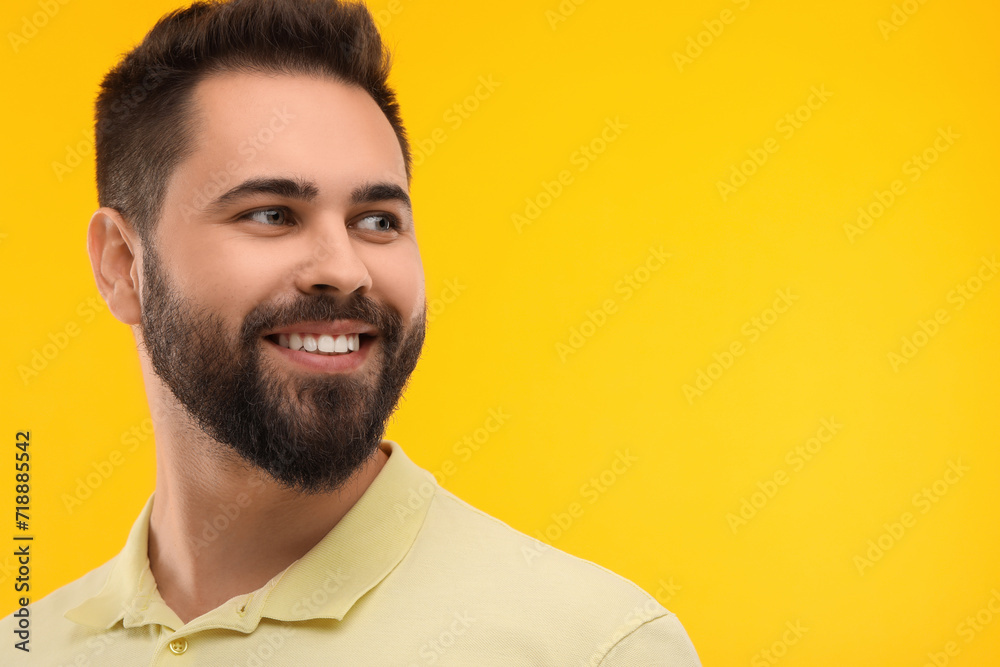 Obraz premium Man with clean teeth smiling on yellow background, space for text