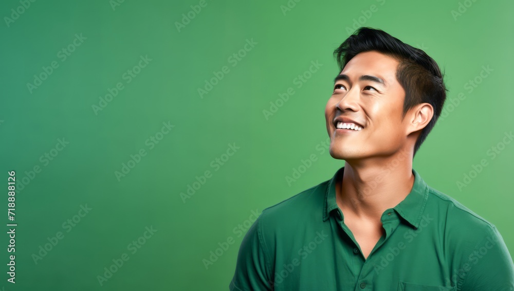 Side view of attractive adult Asian man smile isolated on green background. Side view of attractive adult Asian man smile isolated on green background.
