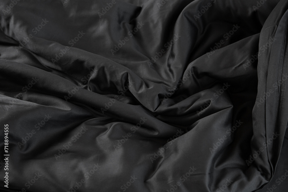Texture of black satin bed linen with waves fabric