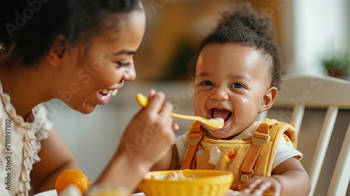 Mother lovingly feeds joyful toddler with spoon at home, maternal care photo