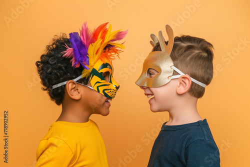 Two children of different ethnicities, profiled looking at each other with tiger and deer masks on a peach-colored background, at a birthday party, carnival or school activity. photo