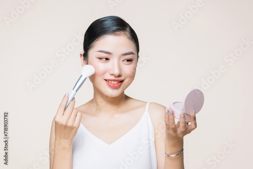Portrait of attractive young adult woman applying blusher