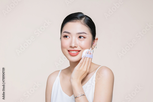 Obraz na płótnie Young asian woman smile looking happy applying makeup with puff makeup on beige background. w salonie