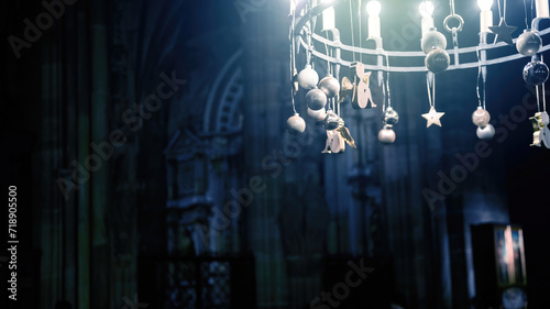 A dimly lit photograph captures an ornate chandelier adorned with figures and stars, hanging inside a cathedral with gothic architecture elements. photo