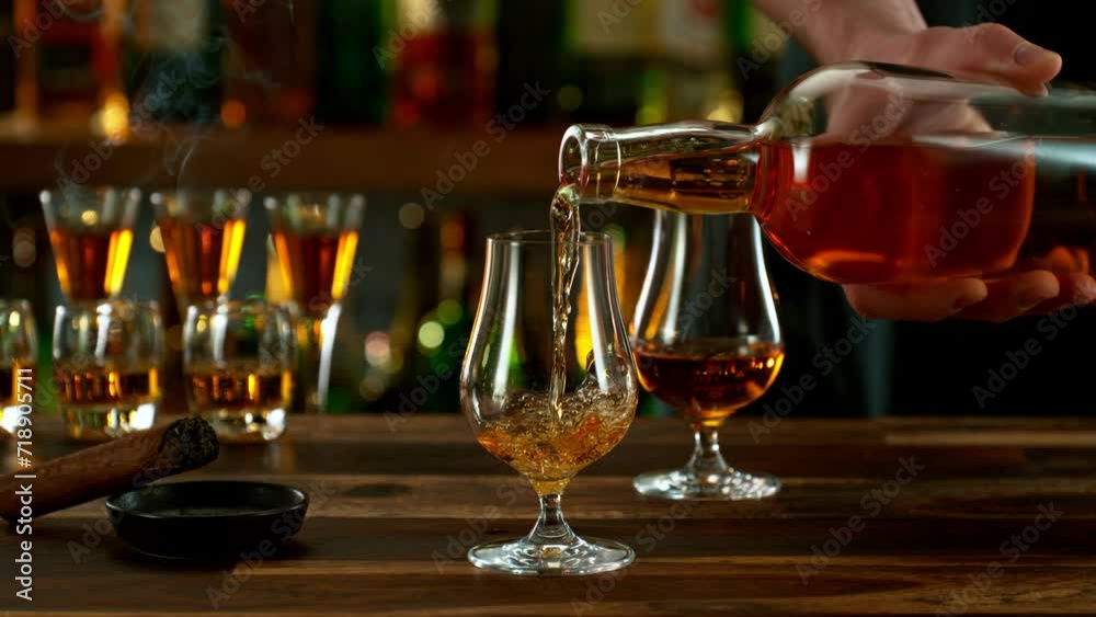 Super slow motion of pouring cognac into glass with speed motion. Filmed on high speed cinema camera, 1000 fps, placed on high speed cine bot. Bar with bottles on background. Super slow motion of pouring cognac into glass with speed motion. Filmed on high speed cinema camera, 1000 fps, placed on high speed cine bot. Bar with bottles on background.