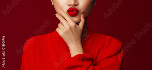 Matte lipstick. Blowing kiss. Fashion portrait of young asian model with lips make up posing with a chin look against red background.