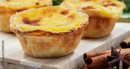 Pastel de nata tarts or Portuguese egg tart on a wooden brown background. Pastel de Belem is a small pie with a crispy puff pastry crust and a custard cream filling. Sweet dessert.
