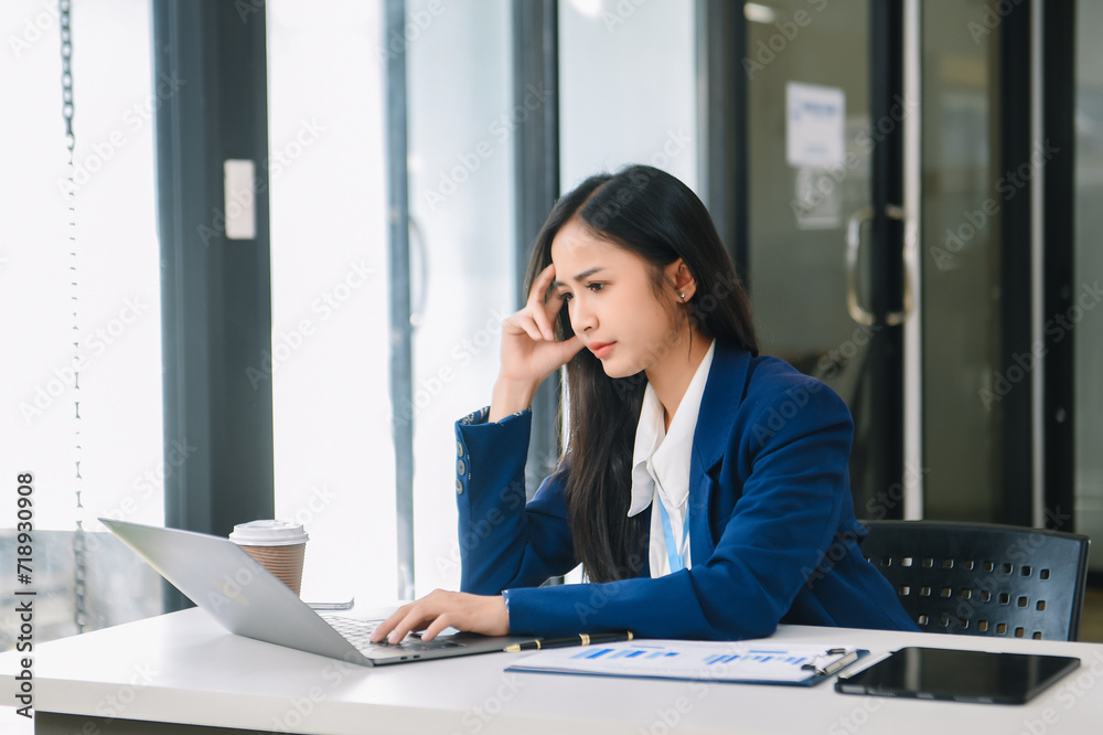 Frustrated young businesswoman working on a laptop computer sitting at his working place