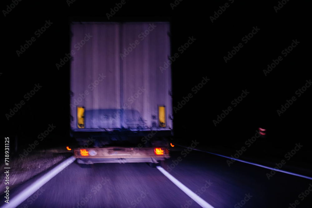A blurred motion capture of a truck traveling on a highway at night ...