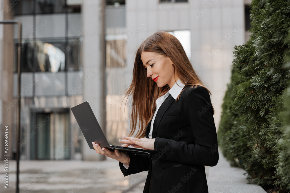 Urban portrait of young business woman works in a laptop outdoor of modern office center background Urban portrait of young business woman works in a laptop outdoor of modern office center background