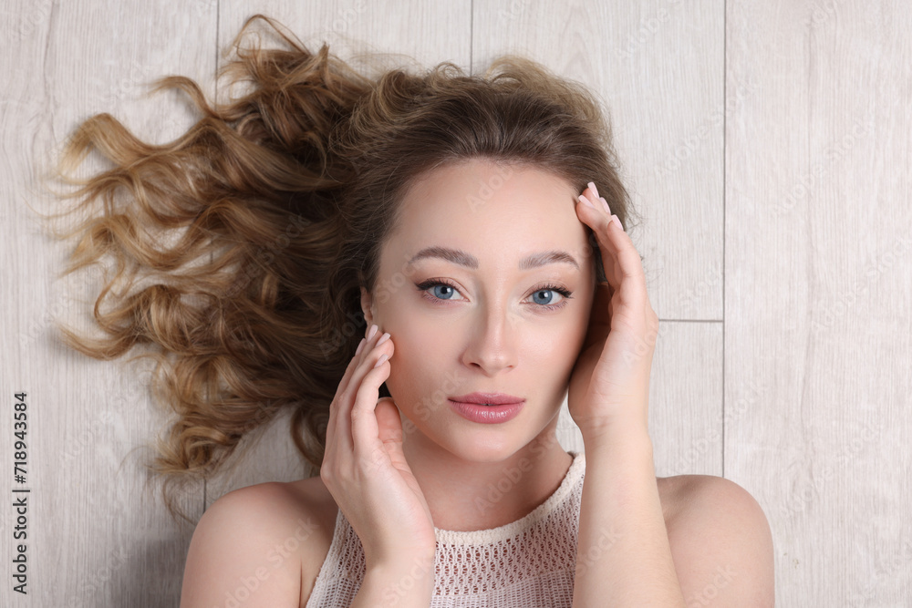 Obraz premium Portrait of beautiful woman with curly hair on wooden floor, top view