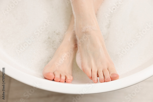 Woman taking bath with foam in tub, top view