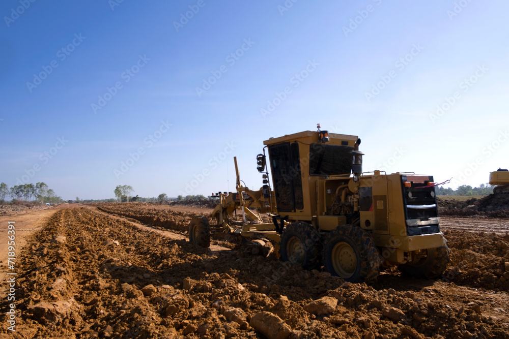 Road grader is pushing dirt. Motor grader is working,smoothing gravel surface for new road. Road grader is pushing dirt. Motor grader is working,smoothing gravel surface for new road.