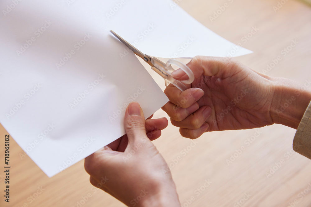 Obraz premium ハサミで紙を切る女性の手元