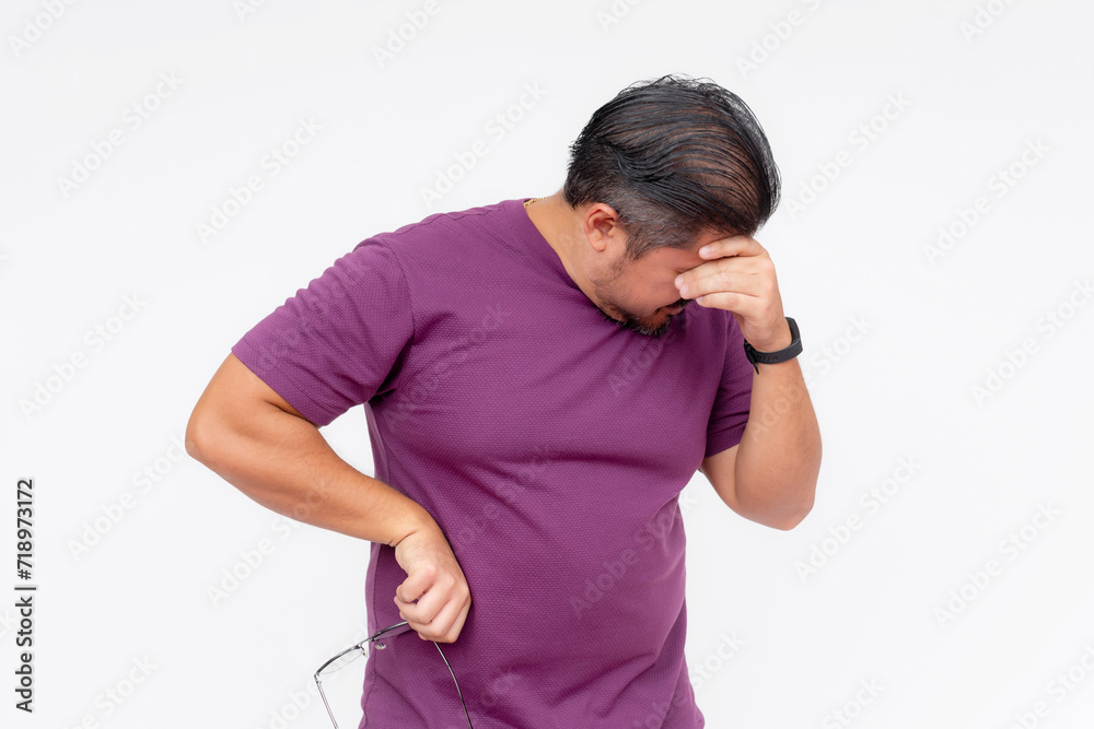 An adult man looking strained and touching his forehead, signaling a headache or stress, isolated on white. An adult man looking strained and touching his forehead, signaling a headache or stress, isolated on white.