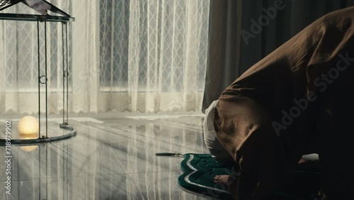 Muslim Woman in Hijab Praying on a Prayer Mat at Home at Night, Bowing