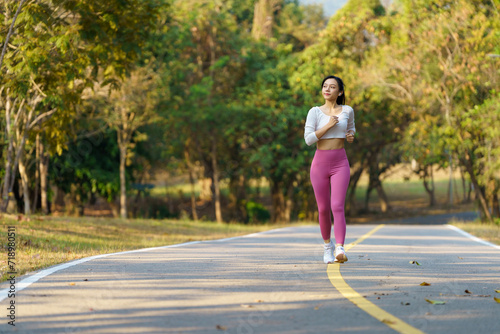 Asian woman jogging in the park smiling happy running and enjoying a healthy outdoor lifestyle. Female jogger. Fitness runner girl in a public park. healthy lifestyle and wellness being a concept.
