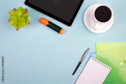 Tablet, calculator, phone, pen and a cup of coffee, lot of things on a blue background. Top view with copy space.
