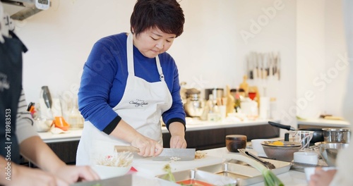Japanese chef, woman and kitchen with knife, cooking and prepare ingredients for catering services. Person, food and chopping board for nutrition, diet or health with job in restaurant, cafe or diner