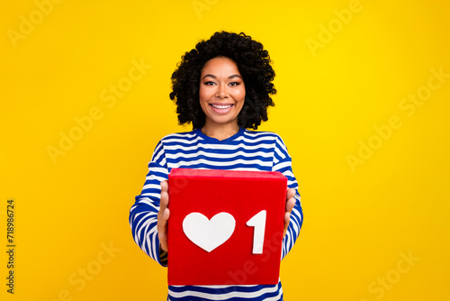 Photo of charming positive adorable girl blogger wear stylish striped clothes demonstrate red card isolated on yellow color background