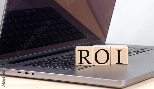 ROI word on wooden block on laptop, business concept