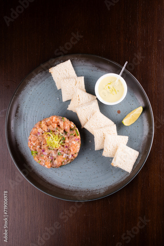 raw salmon tartare with toast sauce and lemon top view