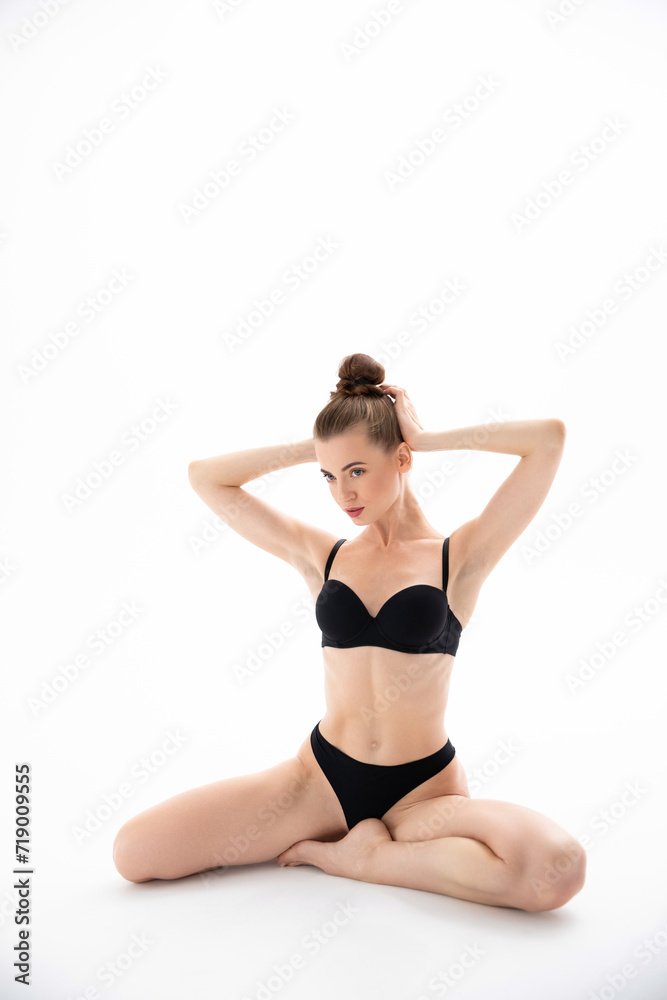Girl in black underwear sits and poses on a white background