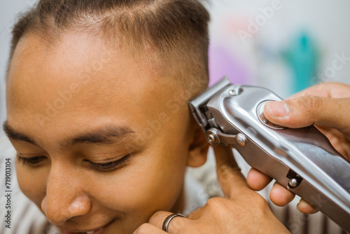 asian male customer getting hair cut in barbershop cropped view