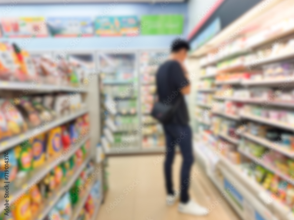 Blurred image of a man walking in a supermarket in a supermarket aisle with a back view of a man shopping in a department store.
