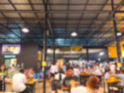The picture blurs the atmosphere inside a Korean BBQ restaurant with many people eating and coming over.